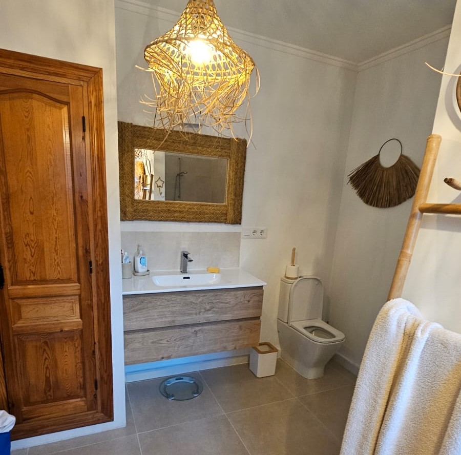 Baño reformado con detalles en madera y estilo moderno.
