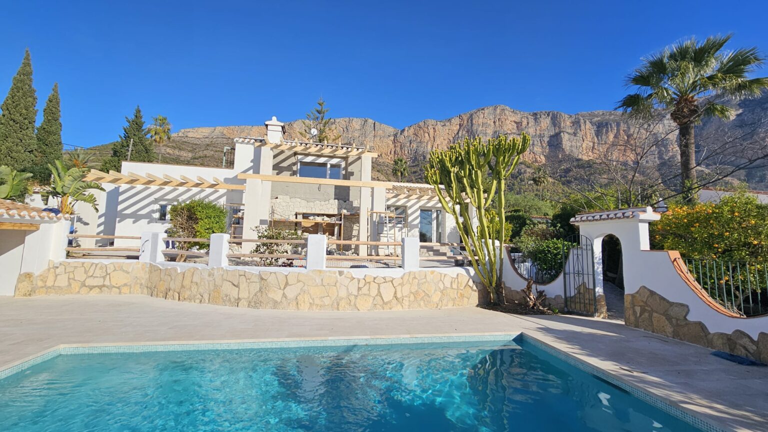 Piscina junto a fachada de piedra en vivienda reformada.