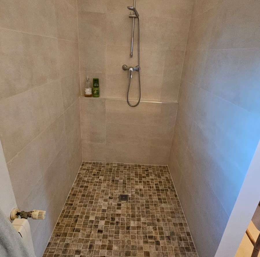 Ducha de obra reformada con suelo antideslizante y acabado cerámico.